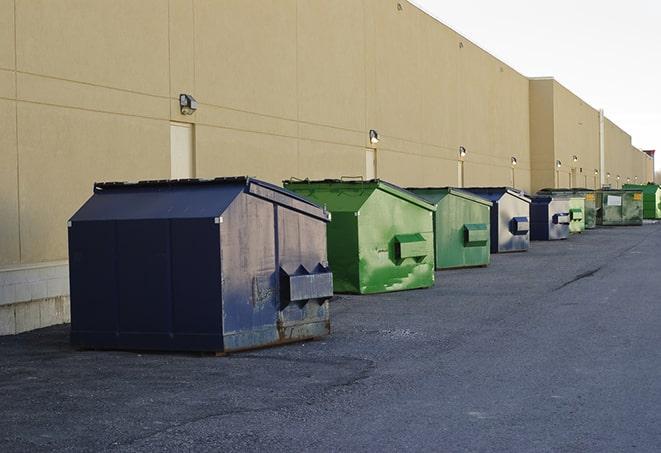 construction workers toss wood scraps into a dumpster in Evans, CO